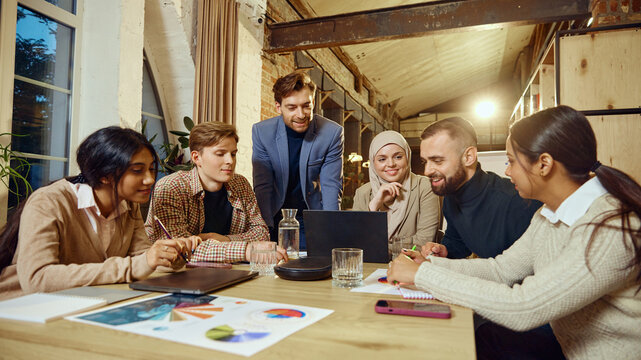 Professionals participate in business planning session, using graphs and charts for effective strategy. Multiracial group, modern workspace. Concept of dei in business, teamwork