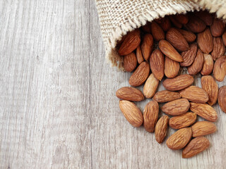 Natural brown fresh almonds on woven jute fabric