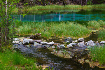 Summer landscape with Geyser Lake in the Altai Republic, Russia. The lake is also called Silver or Blue Lake. The water in the lake is turquoise