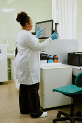 Obraz premium Scientist conducting research by utilizing laboratory equipment in a modern lab setting with various instruments and materials around. She wears lab coat and safety gloves