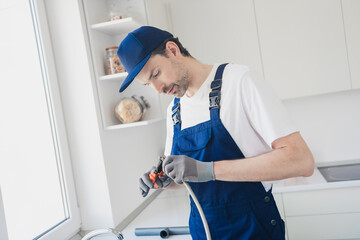 Dedicated young handyman skillfully performing plumbing tasks during a home renovation in a bright kitchen setting