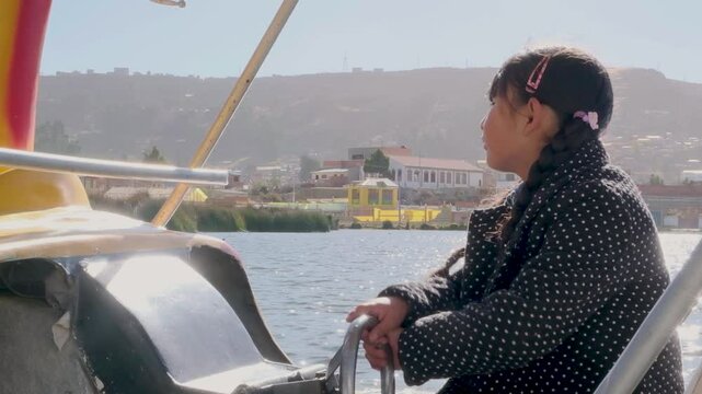 latin girl driving a boat on a lake titicaca  in daylight in la paz bolivia - adventure concept