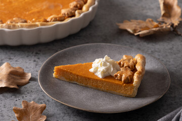 Piece of American Pumpkin Pie on gray background. Traditional dessert for Thanksgiving Day. Close up.