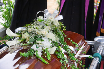 flowers on a coffin at the grave priest to bless the grave