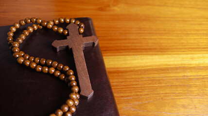 Dark brown wooden cross on a dark brown book symbolizing the spread of Jesus Christs love among Christians reflecting faith devotion and the importance of Christian teachings.