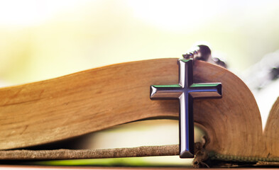Obraz premium Dark metal cross on an old open book symbolizing the spread of Jesus Christs love among Christians reflecting faith devotion and the importance of Christian teachings.