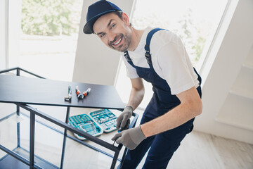 Smiling handyman assembling furniture in bright modern home with set of tools, demonstrating skill craftsmanship in home renovation