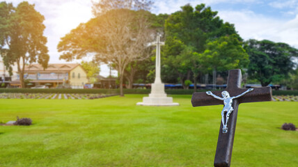 A red wooden cross on a blurred cemetery background.