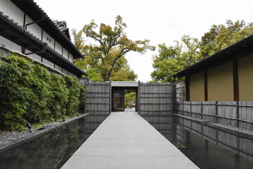 Pathway by Water Leading to a Japanese Style Door in a Traditional Japanese Garden