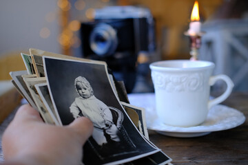 female hand holding set old family photos in vintage interior, stack nostalgic sentimental pictures, photographs 50s, retro accordion camera, concept genealogy, memory ancestors, family tree