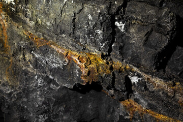 dettagli di una parete di roccia dal colore grigio scuro e nero e con alcune venature di colore arancione e marrone