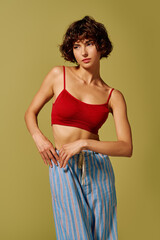 A young woman flaunts her emotions in a chic red crop top and relaxed striped pants.