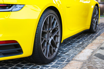 Fototapeta na wymiar Bright yellow premium car on cobblestones, close-up.