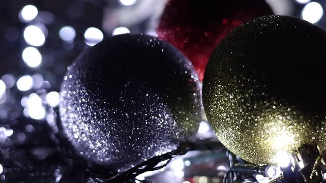 Una toma de cerca de tres bolas de navidad de diferentes colores rodeada de luces de varios colores con un fondo desenfocado.  Decoraci&oacute;n de navidad y fin de a&ntilde;o