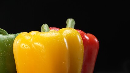 Macro of fresh bell peppers in this stunning macrography against a black background. Each close-up shot captures the rich hues, intricate textures, and captivating details of bell peppers. Comestible.