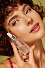 A young woman with curly hair tenderly applies serum to her skin, radiating beauty and confidence.