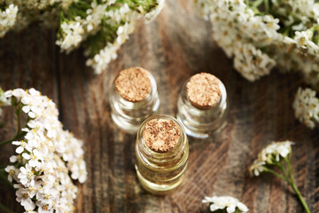 Bottles of aromatherapy essential oil with yarrow flowers