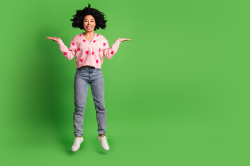 Full body photo of attractive young woman jump compare empty space dressed strawberry print clothes isolated on green color background