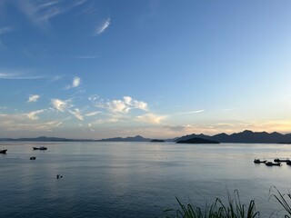 Calm Evening Sea with Distant Mountains and Sunset Sky.