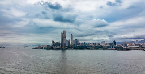 Fototapeta premium View of Hong Kong skyline with cloudy skies and water reflections in the late afternoon