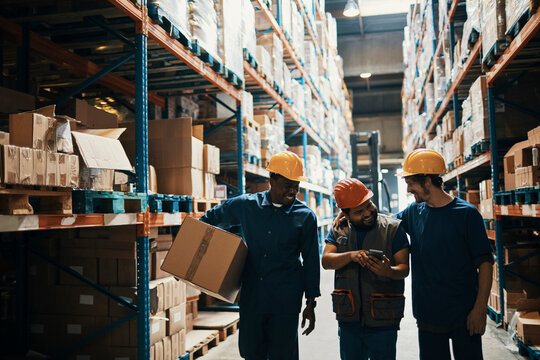 Warehouse workers with hard hats sharing a laugh on break - Powered by Adobe