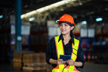 A woman in a safety vest and helmet is holding a tablet. She is smiling and she is happy