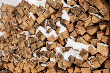 birch firewood. neatly stacked pile of firewood is partially covered in snow, a cold winter environment. warmth for cozy evenings in a rural setting