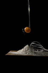 YEMA DE HUEVO CAYENDO CON HARINA ABAJO CON FONDO NEGRO