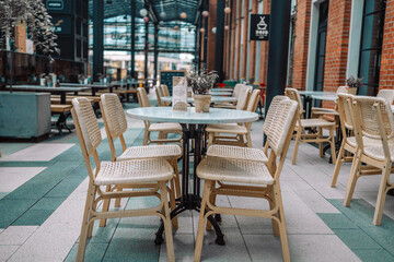 Wooden chairs with a green flowers in the middle of the table of an outdoor restarurant. High quality photo