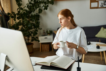 A young man sits at his desk, sipping coffee and focusing on his work in a stylish workspace.