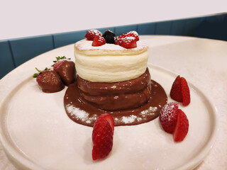  Delicious sweet Japanese dessert, round egg fluffy airy pancakes with chocolate sauce and strawberries, on a white plate