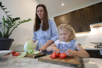 Mother and small daughter cooking food 