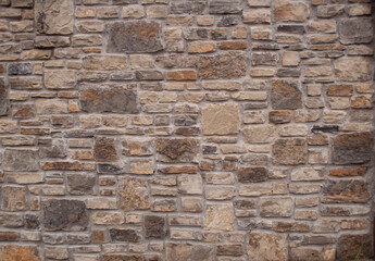 Colorful thin cut stone brick wall with streams of water running down the surface
