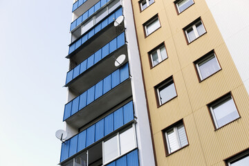 High block of flats background. Skyscraper living area in retro style with metal sheet cladding and unique facade design. Urban living in older neighborhoods. Tv antennas on balcony.