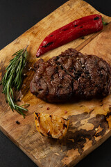 Tasty grilled Rib Eye Black Angus served with pepper and herbs on wooden board.