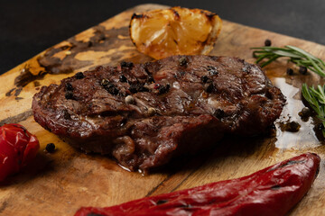 Tasty grilled Rib Eye Black Angus served with pepper and herbs on wooden board.