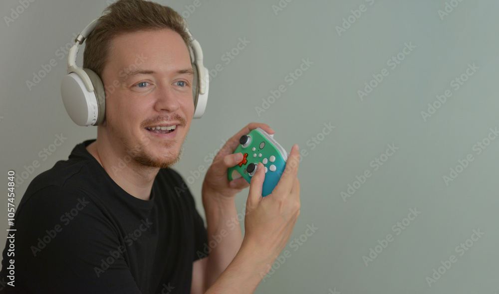 Wall mural a young man wearing headphones playing video game by console controller. gamer with joystick and smi