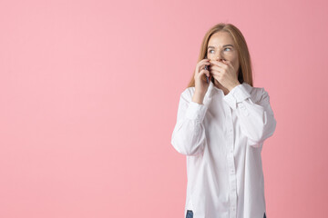 Lifestyle, technology concept. Curious young lady in a white shirt gazes above while speaking with mobile phone, hands cupped near mouth