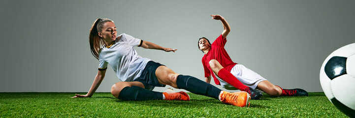 Dynamic image of two young women, soccer players in white and red jerseys, competing on field, showing skills and motivation to win. Concept of sport, action, competition, game