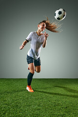 Female soccer player kicking ball with head. Woman in wet uniform, symbolizing rainy weather...