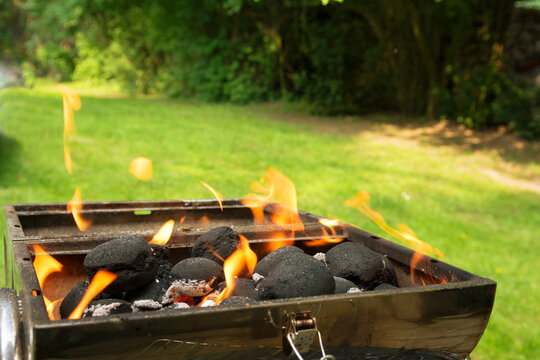 Burning coal briquets on grill in garden