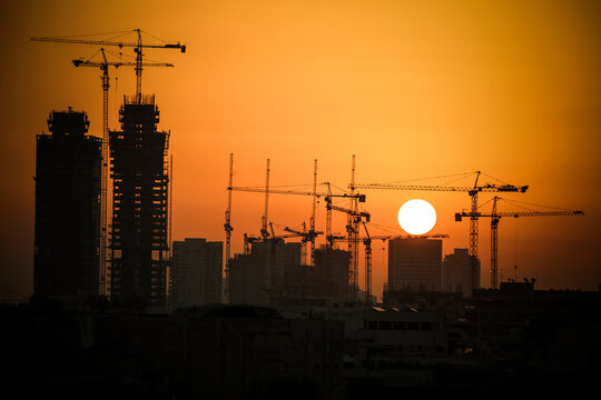 Israel, Tel Aviv, cityscape with cranes at sunset