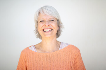 Close-up of smiling woman in orange sweater on white background