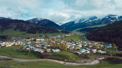 Fototapeta premium A tranquil village nestled in the mountains of Kyrgyzstan during a cloudy day in spring