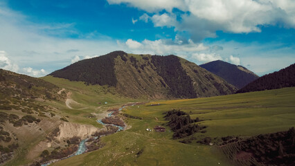 Fototapeta premium Beautiful landscape of Kyrgyzstan with rolling hills and a winding river under a blue sky