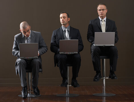 Three Businessmen Using Laptop Computers