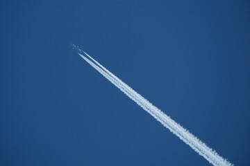 Airplane in the blue sky, with contrail 