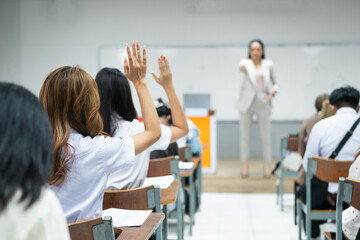 Students Raising Hands in Classroom with Teacher Presenting