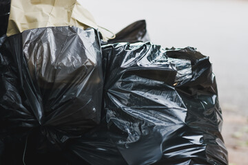 Black plastic garbage bags are placed on the side of a public road.