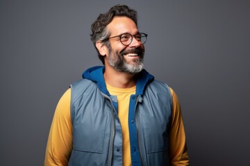 Obraz premium Portrait of a cheerful man in his 40s dressed in a water-resistant gilet over blank studio backdrop